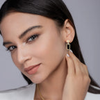 Woman wearing gold earrings with a neutral background