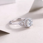 Silver ring with a large diamond and smaller stones on a light background
