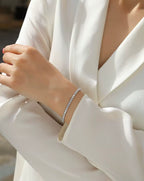 Close-up of a person wearing a silver bracelet on a white outfit.