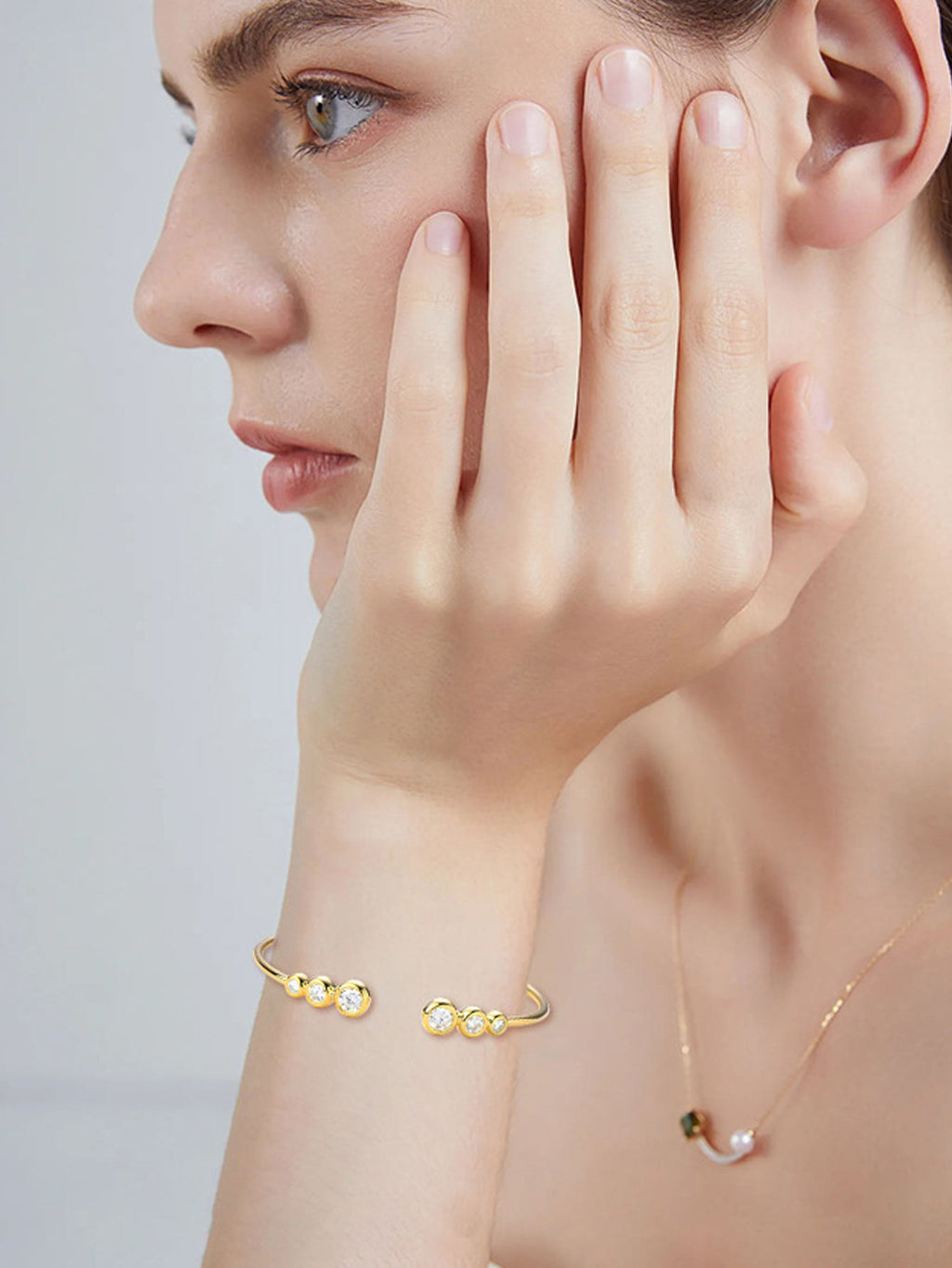 Close-up of a person wearing gold jewelry on a plain background